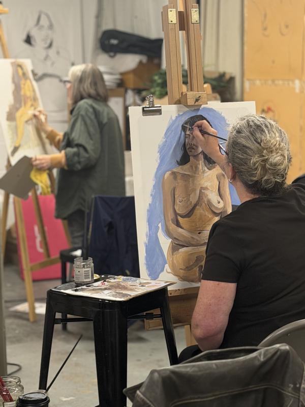 Two artists at their easels painting a nude life model in oil paints