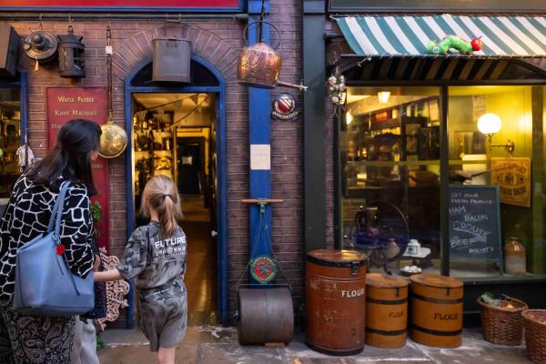 An adult and child looking through a walkway in victorian streets