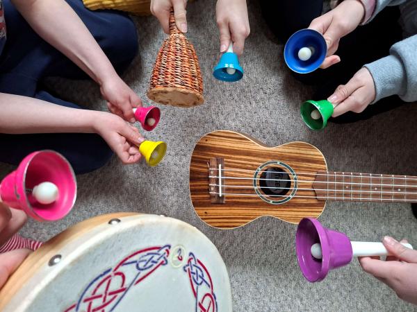 Children holding a ukelele and bells.