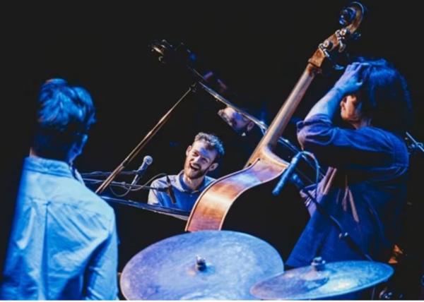 Nils Kavanagh on piano smiling with his trio