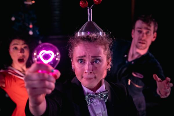 Three people looking confused at a lightbulb heart