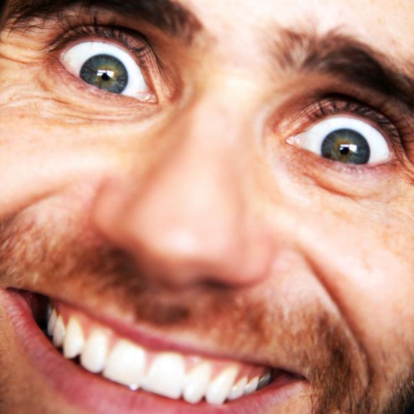 Close-up of Tom Lawrinson manically grinning with wide eyes.
