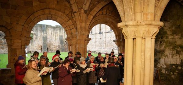 An image of the Heritage Singers in the Abbey's Chapter House singing carols