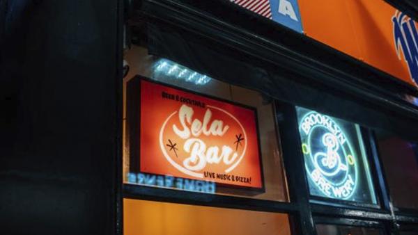Outdoor light boxes saying 'Sela Bar' and 'Brooklyn' 