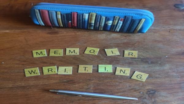 A photo of a pencil case and scrabble letters forming the words "Memoir Writing"