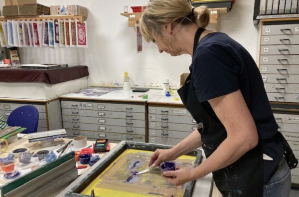 An artist adding ink to a screen