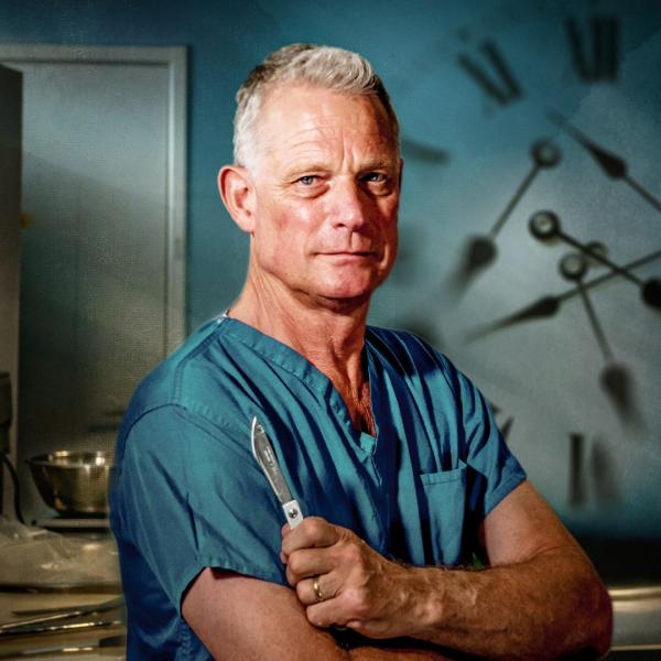 Dr Richard Shepherd stands with arms crossed, holding a scalpel and wearing blue scrubs in a clinical setting. A shadowy clock is visible in the background.