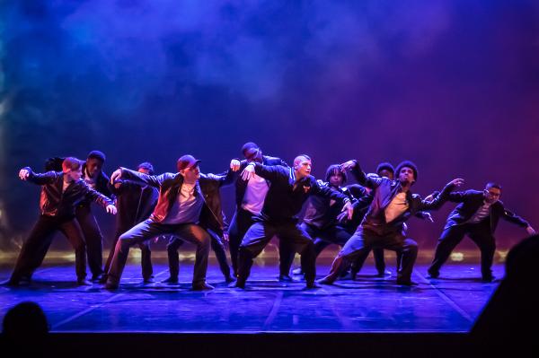 Group of 10 boys in black and white dancing on a stage