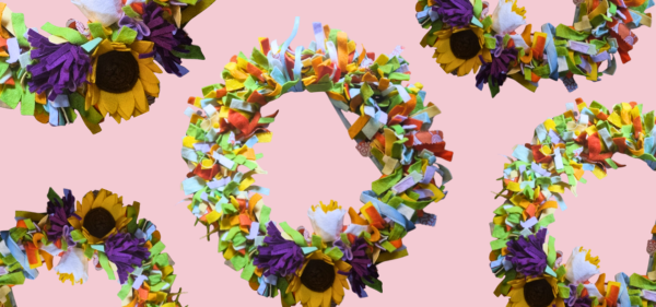 A repeating pattern of colourful felt wreaths with purples, greens, whites, yellows, reds and pinks, against a pink background.