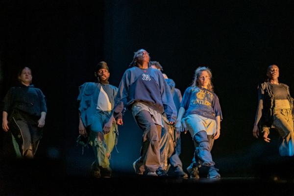 Group of dancers facing forward photographed from below stage