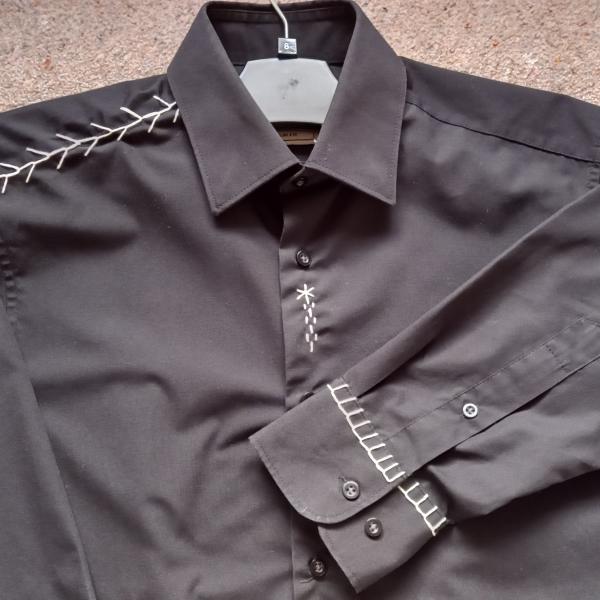 A photograph of a black shirt with white stitching detail