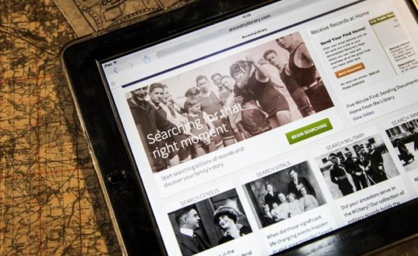 An ipad with the Ancestry.com home page open. The ipad sits on top of an old map.