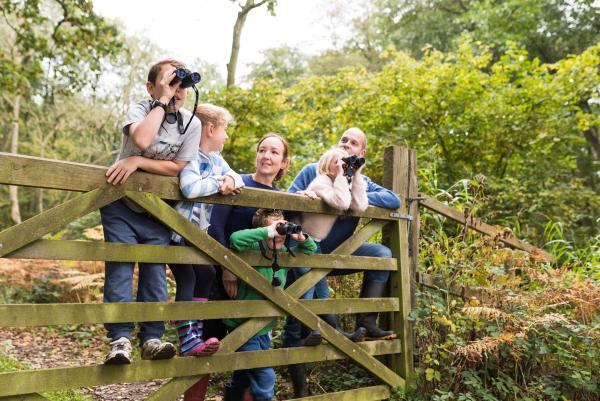 Image shows a family standing behind a fence with binoculars having lots of fun together