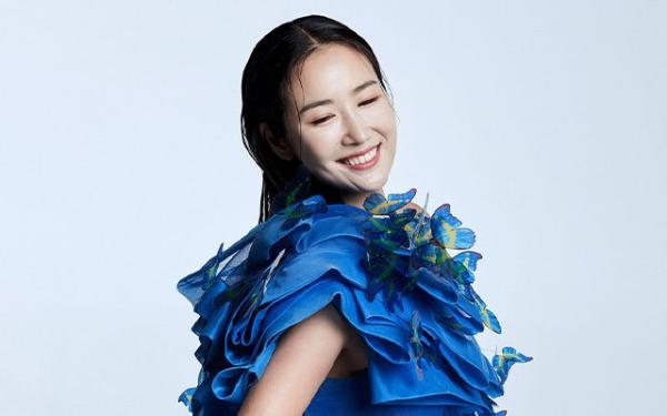 A woman smiling in a blue dress adorned with large decorative butterflies