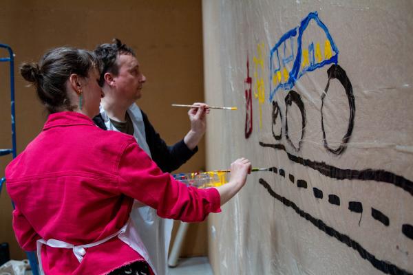Pyramid artists paint a canvas covered wall