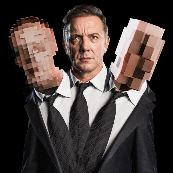 Peter Serafinowicz in a shirt and tie, with two pixelated heads on each shoulder. 