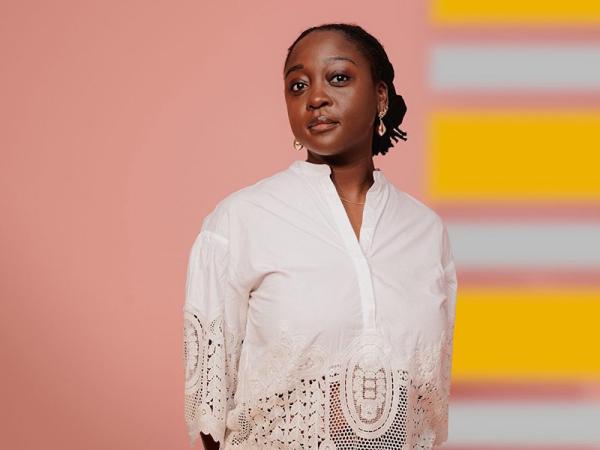 A woman wearing a white shirt standing in front of a colourful background.