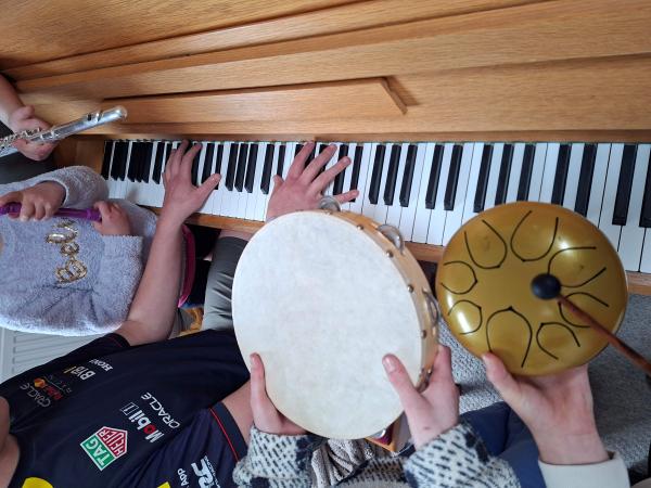 Children playing the piano and tambourines.