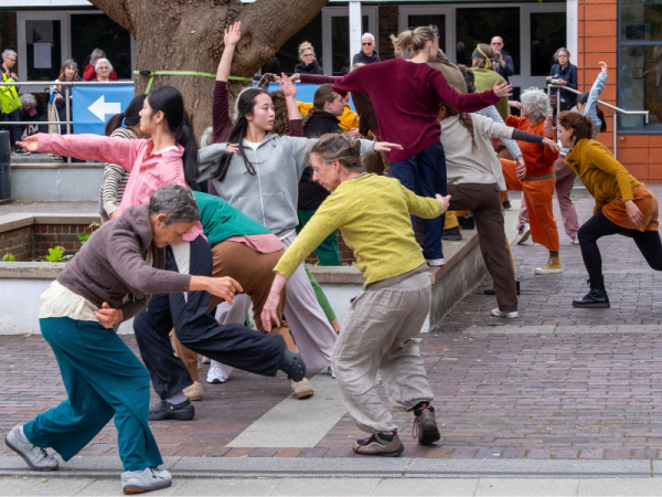a group of people in colourful clothing perform contemporary dance in public