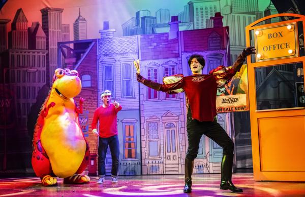 A cartoon dinosaur is using an electric guitar while a boy stands on his back with a microphone