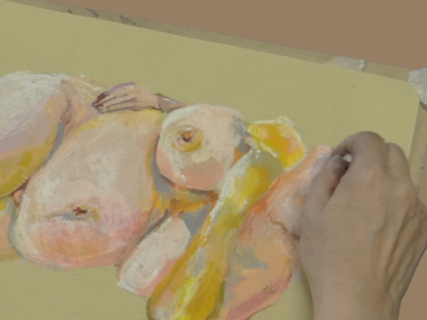 A hand drawing a nude figure in yellow and pink pastels on yellow paper.