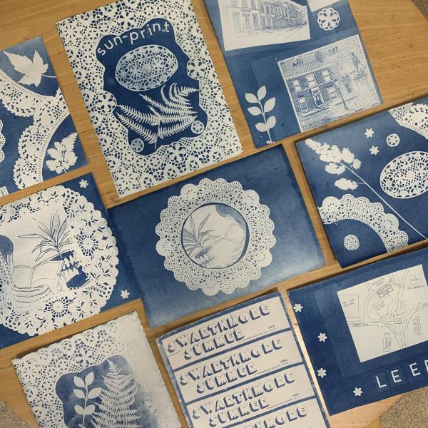 A photograph of a flat lay featuring a selection of blue and white cyanotype prints