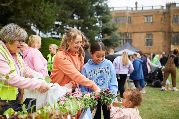 An adult and 2 children buying plants from a stall