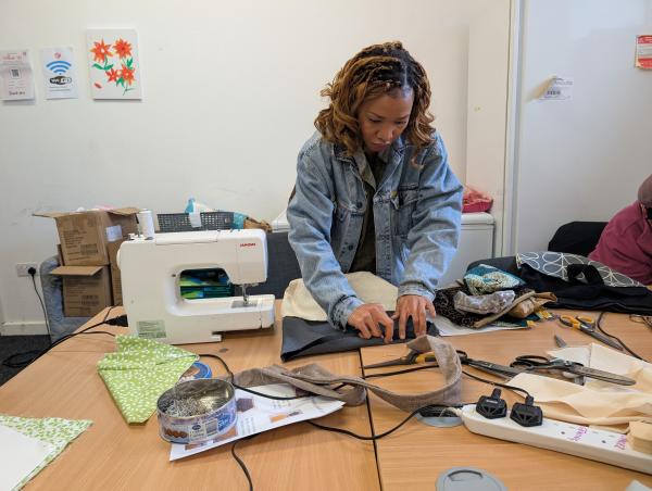 A women pining fabric next to a sewing machine 