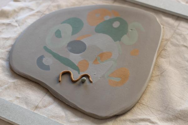 Image shows a slab of rolled out white clay with coloured clay patterns imprinted into it. 