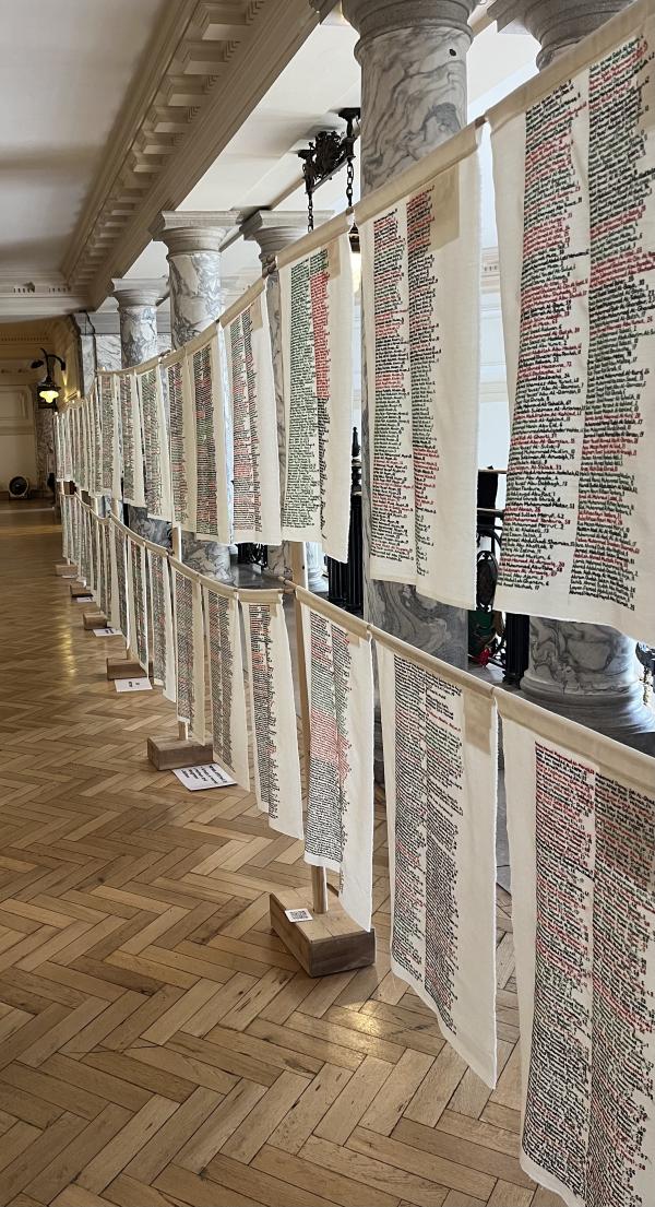 A series of fabric panels, each stitched with the names of adults and children killed in Gaza