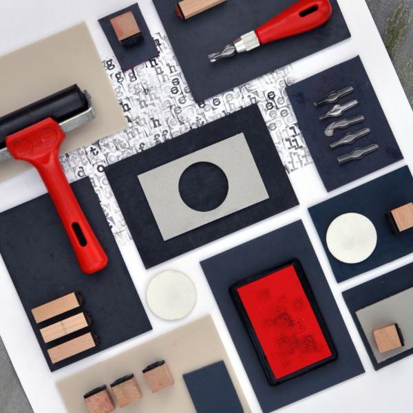 A flat lay photograph of a selection of lino printing tools and materials
