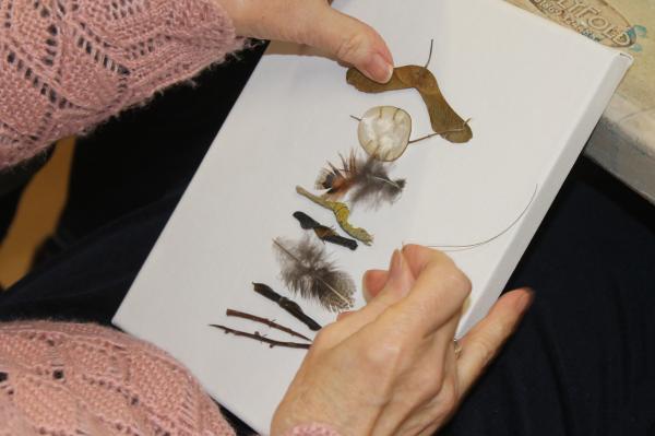 A photograph of a person stitching natural elements on to a canvas