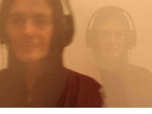 A blurred image of a person in headphones against a wall
