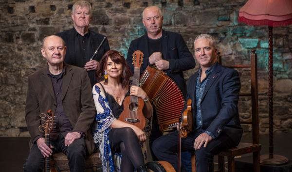 Five piece folk band holding a range of typical folk instruments, their expressions range from moody and contemplative to bemused