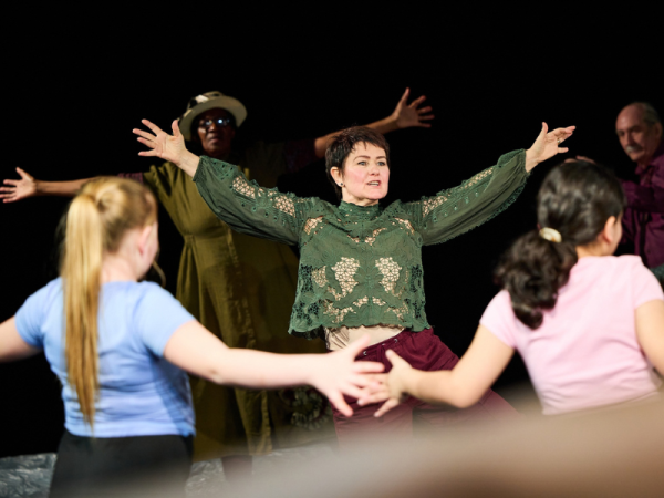 A dancer stands with arms outstretched