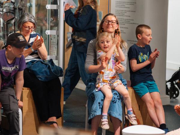 Group of people watching a show all smiling and clapping their hands.