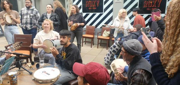 A group of people playing music together inside the Grand Arcade, Leeds