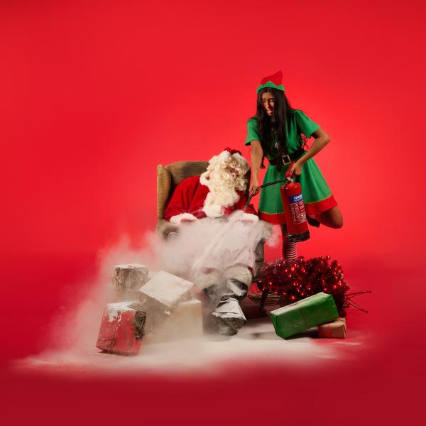 An elf firing a fire extinguisher at Santa