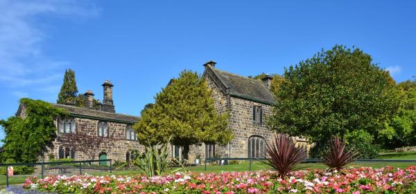 An image of a historic house with clear blue sky and a flower bed in the foreground