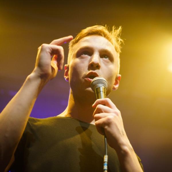 Lence speaks into a microphone on stage.