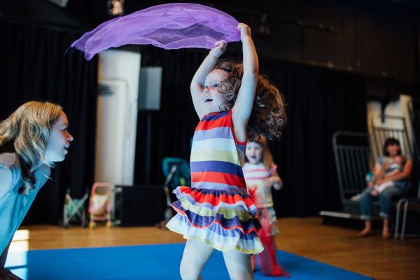A child dancing with a purple scarf