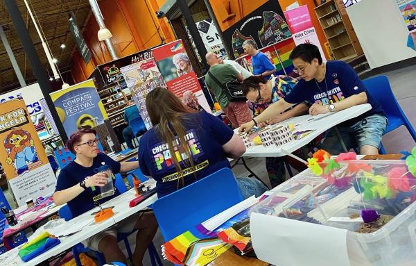 People sat crafting together, with a range of community group banners in background