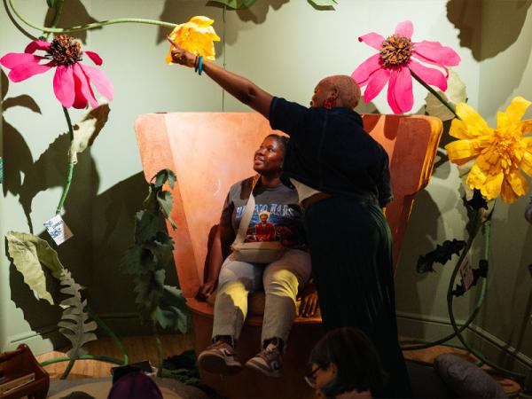 Two people in a museum exhibition about plants, one pointing at a large flower.