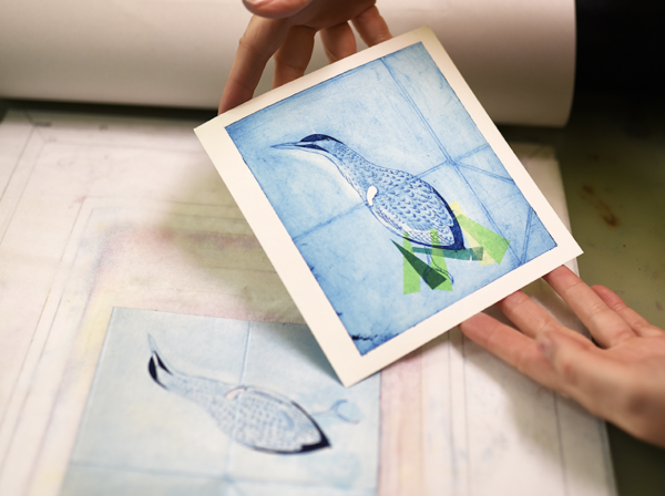 A print of a bird in blues and greens being taken from a design on a Tetra Pak carton