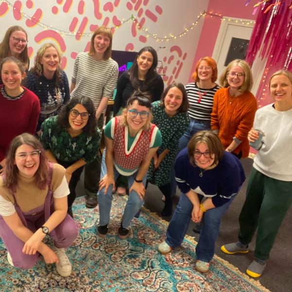 Members of Cosy Choir smiling at the camera in a colourful room
