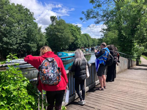People on a bridge looking at canal boats