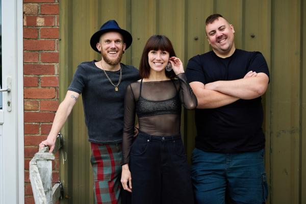 The makers of the show, two men and a woman are standing, smiling at the camera.