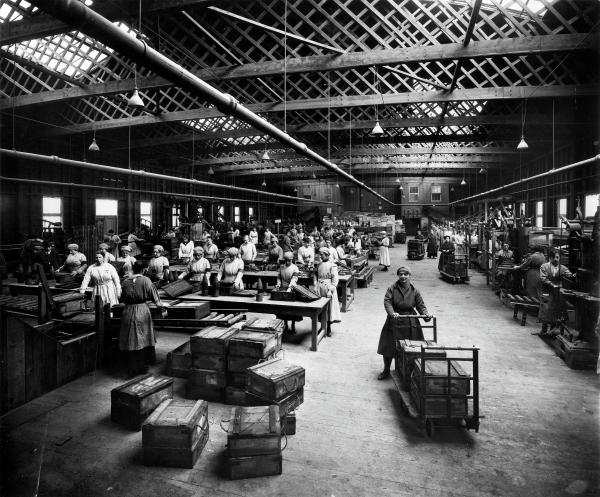 Black and white photograph of the inside of a busy munitions factory.
