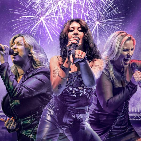 Three women sing into handheld microphones, surrounded by purple haze and fireworks.