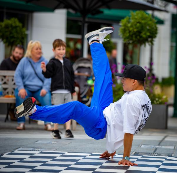 A break dancer performing in blue trousers and white t-shirt